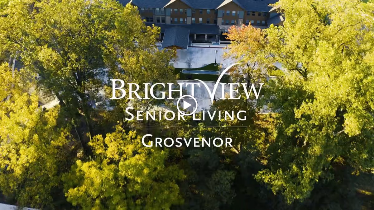 Aerial view of a senior living building surrounded by trees with 'BrightView Senior Living Grosvenor' text overlaid.