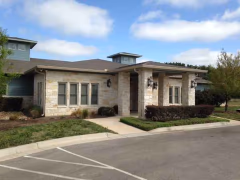 A single-story building exterior with stone facade, entryway and manicured landscaping.