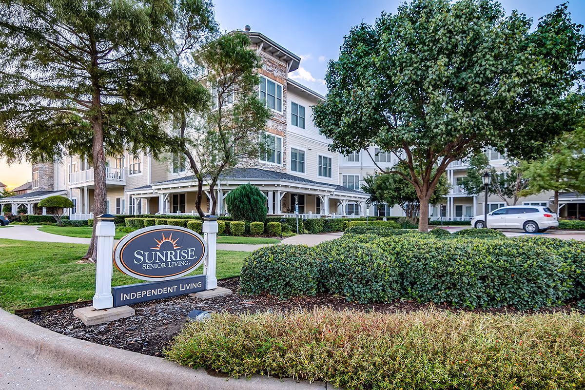 Front exterior of the Sunrise Senior Living building with landscaping and an 'Independent Living' sign in the foreground.