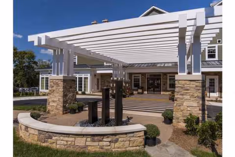 Front entrance of Brightview Great Falls Assisted Living with white pergola and stone pillars.