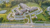 Aerial view of The Summit senior living campus showing multiple connected buildings, parking lots, landscaped grounds, and a roadway in front.