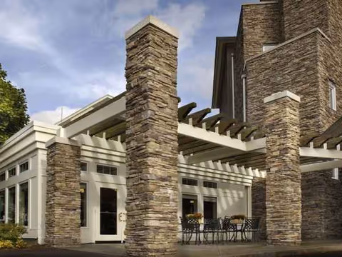 Exterior view of Brookhaven at Lexington featuring stone pillars and a covered seating area.