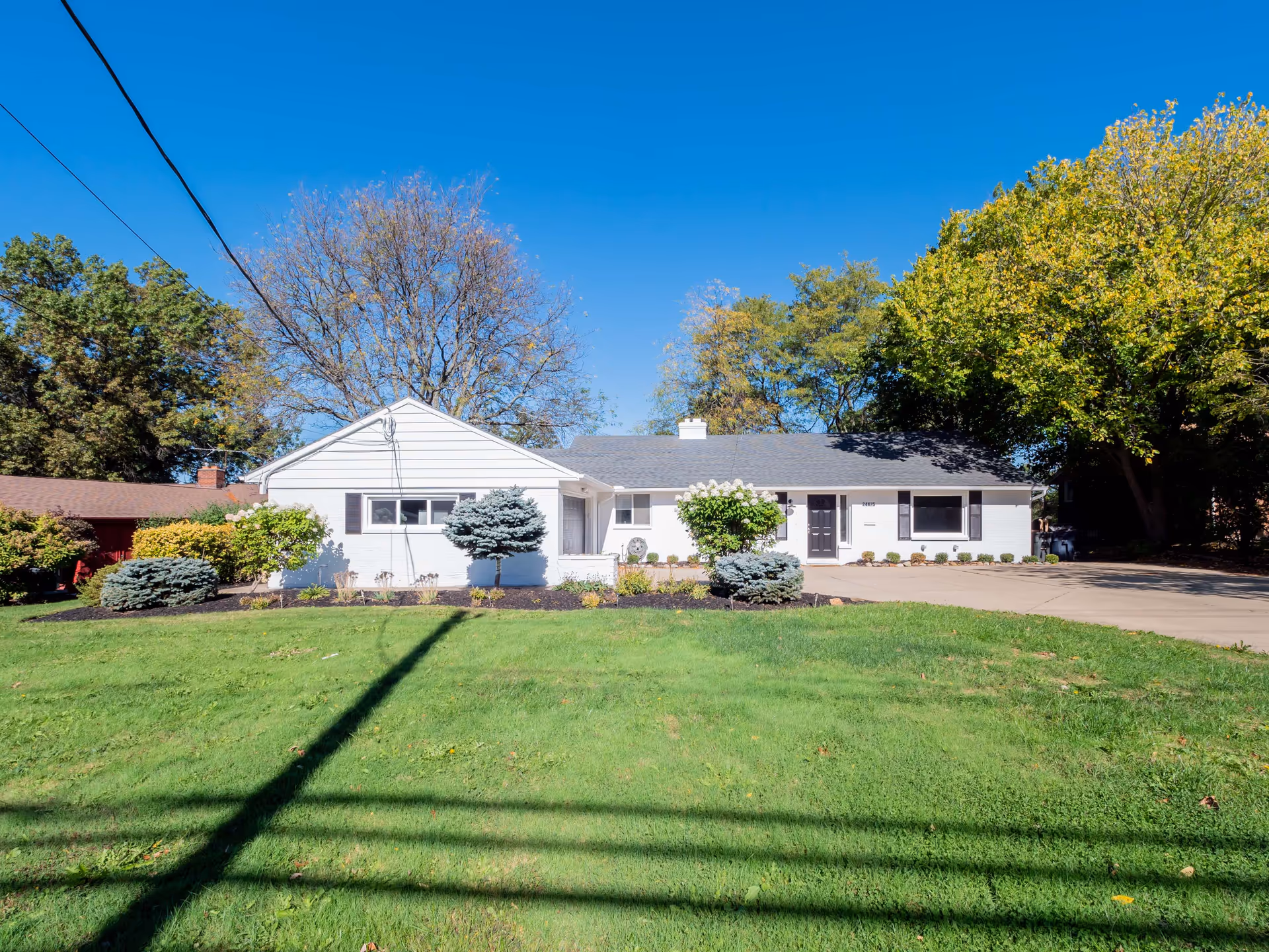Single-story white senior living facility with a manicured front lawn and driveway.
