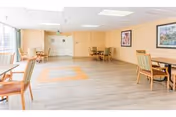 Bright common lounge with multiple tables and chairs along beige walls.