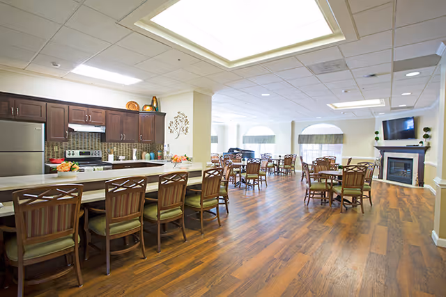 Large open dining room with a kitchen counter and bar stools, multiple dining tables and chairs, and a fireplace with a TV.