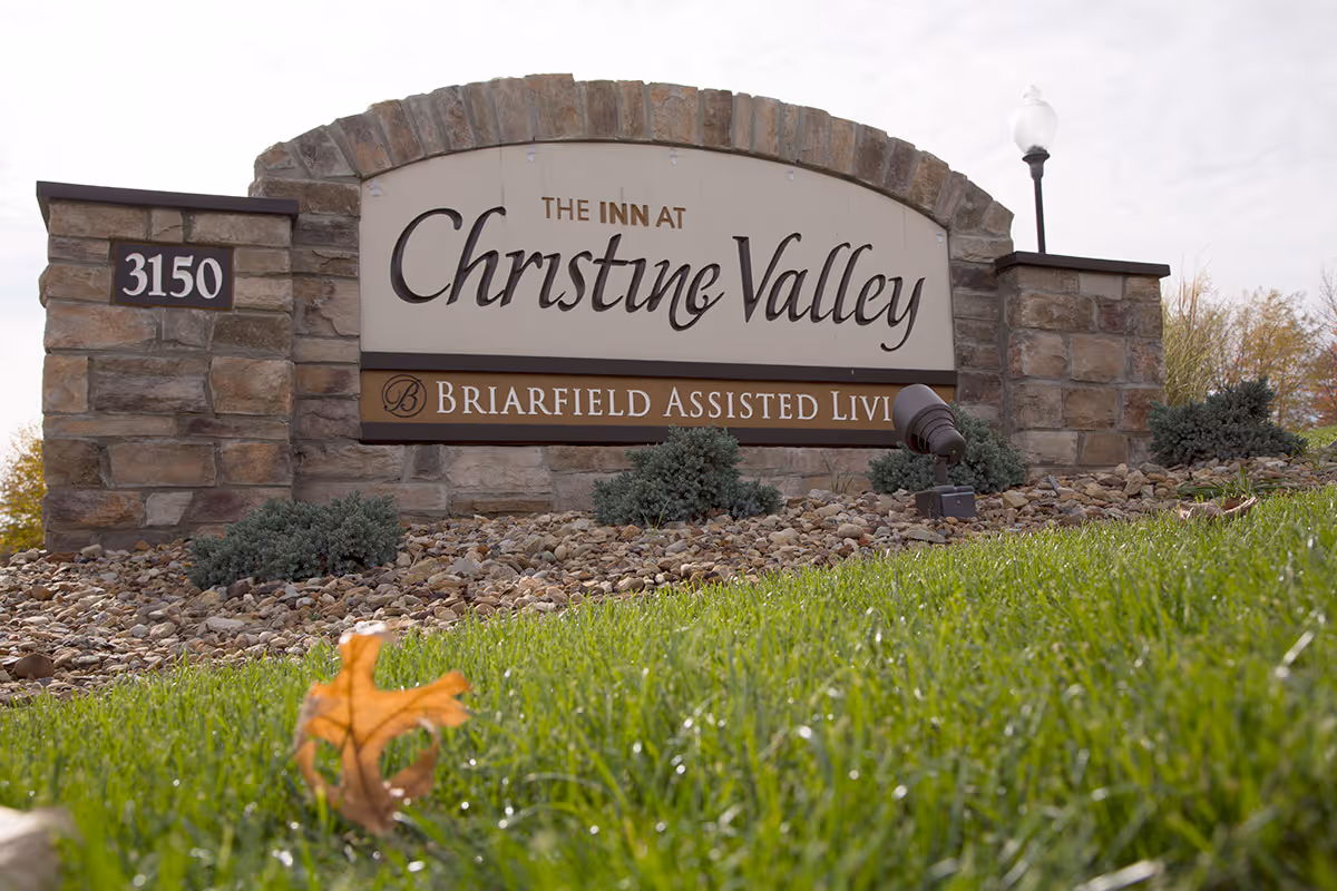 Stone entrance sign reading "The Inn at Christine Valley" and "Briarfield Assisted Living" with address 3150 on a landscaped lawn.