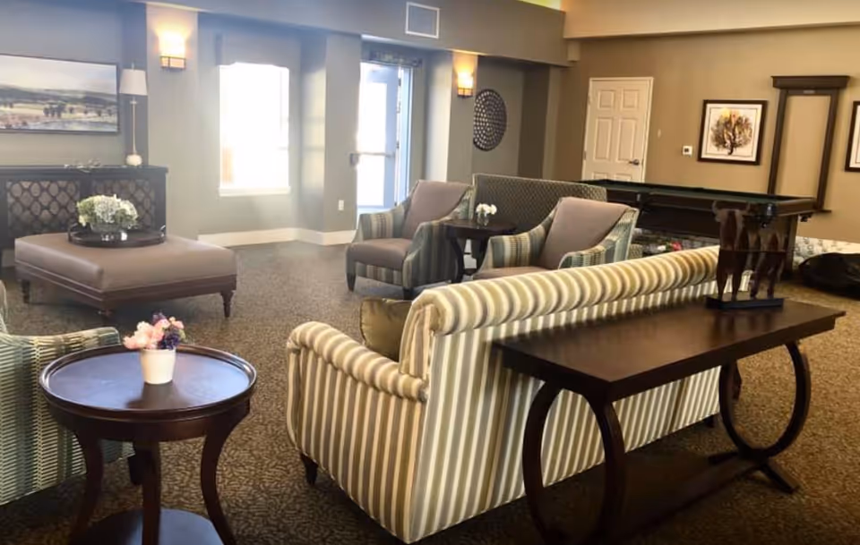 Spacious lounge with striped sofas, chairs, a pool table, and tables.