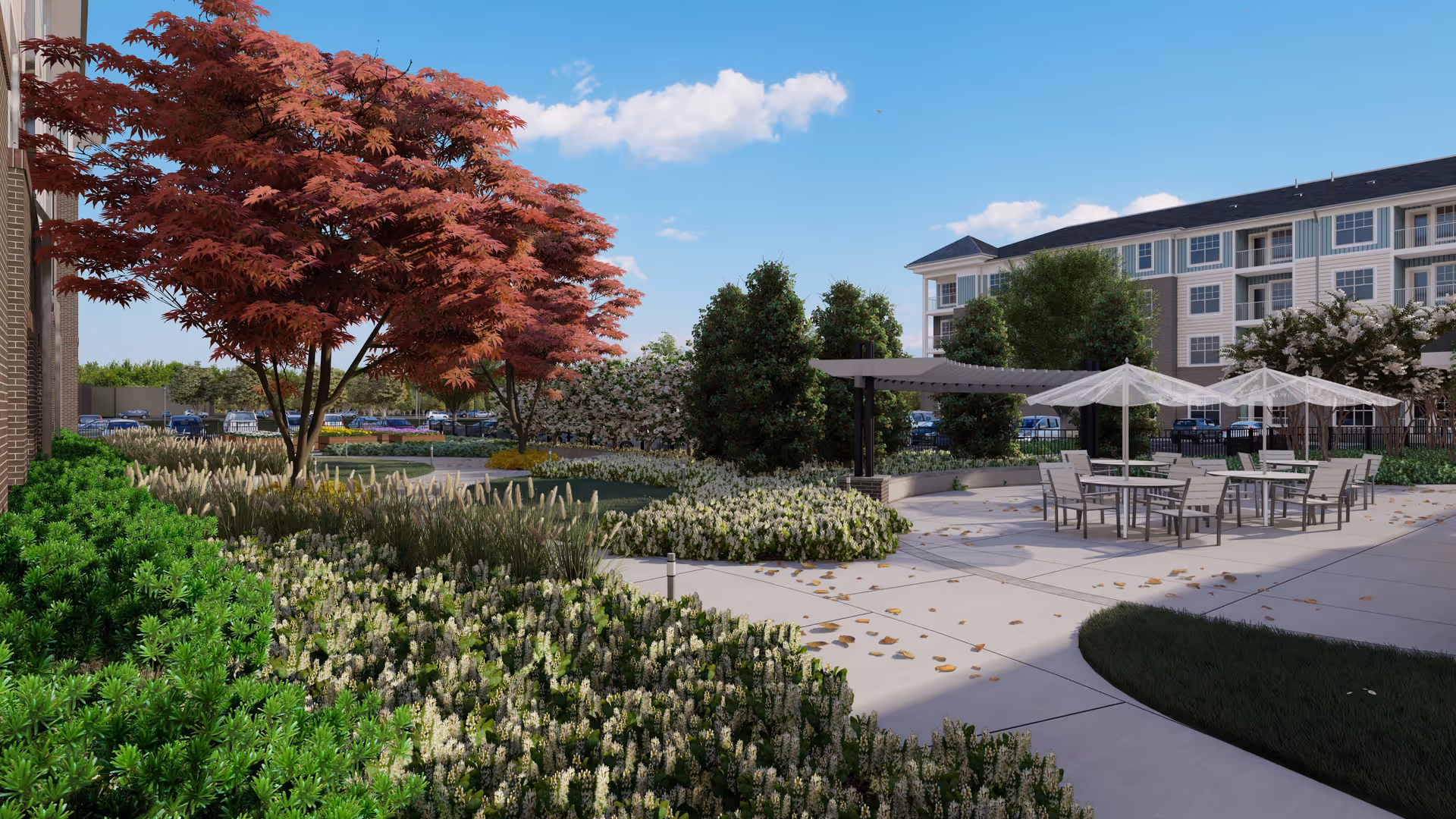 Outdoor courtyard with patio tables and umbrellas, landscaped beds and a multi-story building in the background.