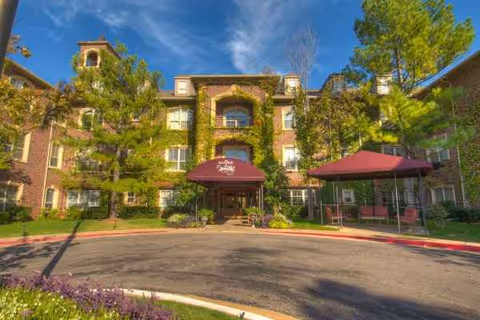 Brick senior living facility with ivy-covered facade, entrance canopies, and a circular driveway.