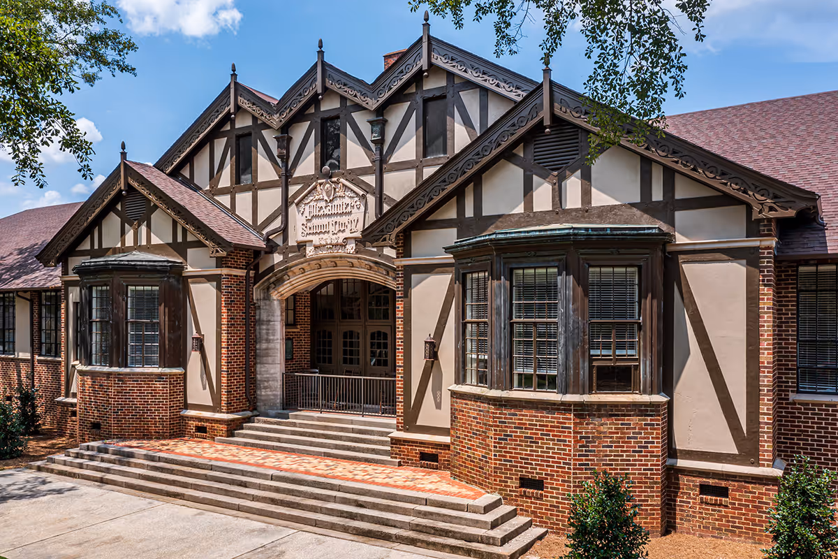 Tudor-style brick building front with a stepped entrance, arched doorway, and decorative half-timbering.