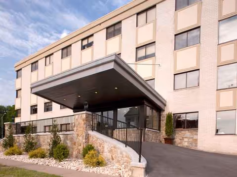 Exterior view of a multi-story senior living building with a covered entrance and landscaped steps
