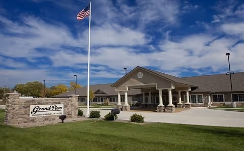 Front exterior of Grand View Alzheimer's Special Care Center with flagpole and driveway.