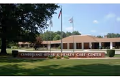 Brick single-story building with a front sign, flags, and a green lawn.
