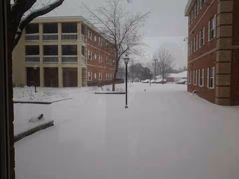 Snow-covered exterior of Ascension Living Via Christi Village with brick buildings and bare trees
