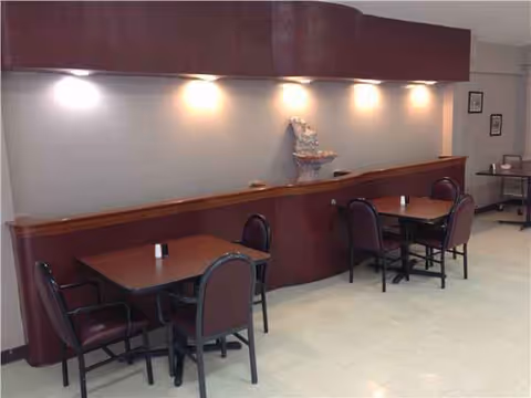 Interior dining area with a long counter, tables, and purple chairs along a wall.