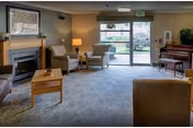 Cozy memory-care living room with sofa seating, a fireplace, and sliding doors.