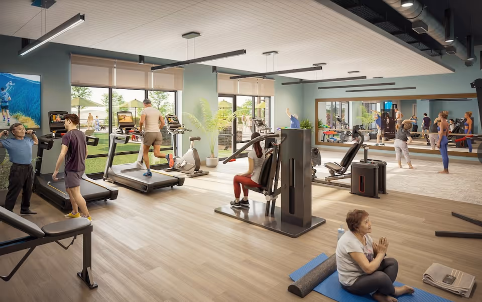 A fitness room with several people exercising using various equipment including treadmills, stationary bikes, and weight machines. Some individuals are stretching or doing yoga on mats near a large mirror. Large windows provide a view of an outdoor area with green grass and umbrellas.
