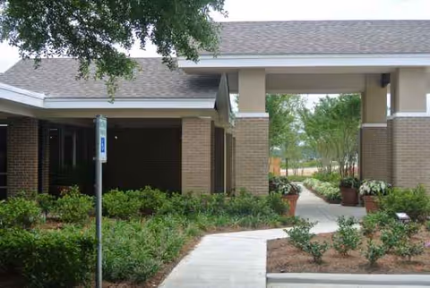 Exterior view of Zachary Manor Nursing and Rehabilitation Center entrance with walkway and landscaping.