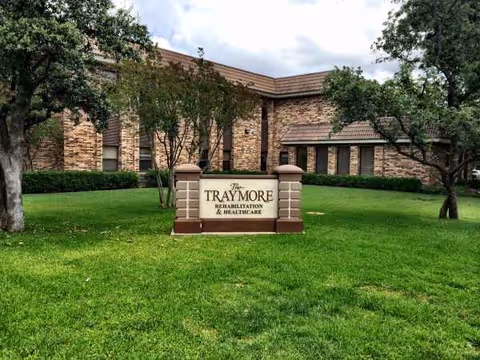 Brick building with a sign reading The Traymore Rehabilitation & Healthcare on a green lawn.
