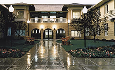 Front exterior of The Argyle showing arched entry, lit walkway, and manicured courtyard.