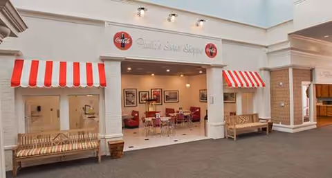Open storefront dining area with red-striped awnings, benches outside, and interior seating visible.