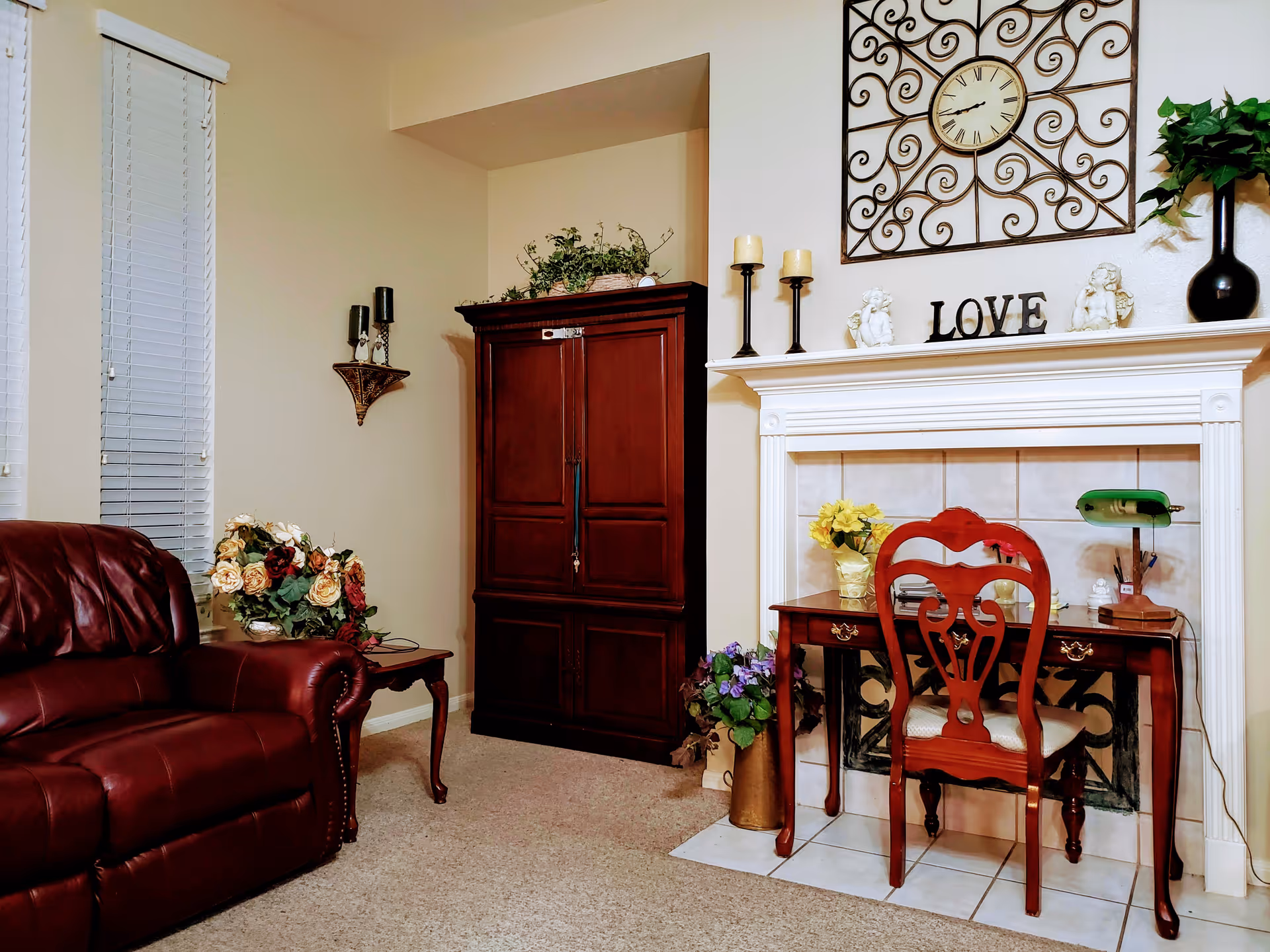 Cozy living room with a leather armchair, wooden cabinet, decorative fireplace mantel and a small desk with a chair.