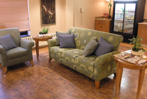 Cozy indoor lounge area featuring a green floral sofa, chairs, tables, and magazines.
