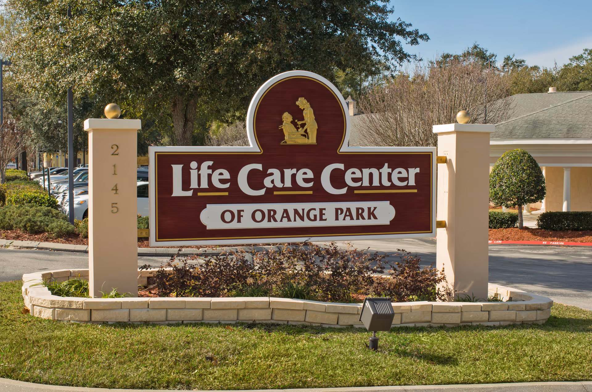 A landscaped entrance sign that reads "Life Care Center of Orange Park" in front of the facility.