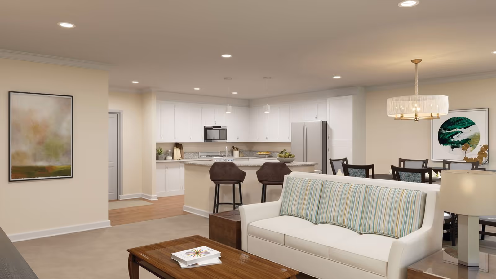 Bright open-concept living area with a white sofa and coffee table facing a kitchen island with bar stools and a dining table in the background.