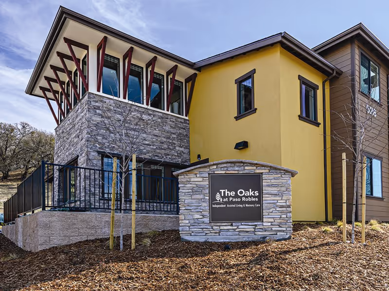 Front exterior of The Oaks at Paso Robles with a stone sign in front of a modern two-story building.