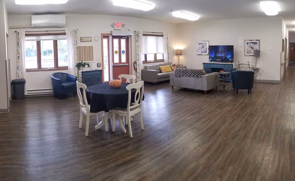 Spacious common living area with round table, pumpkin centerpiece, sofas, and TV.