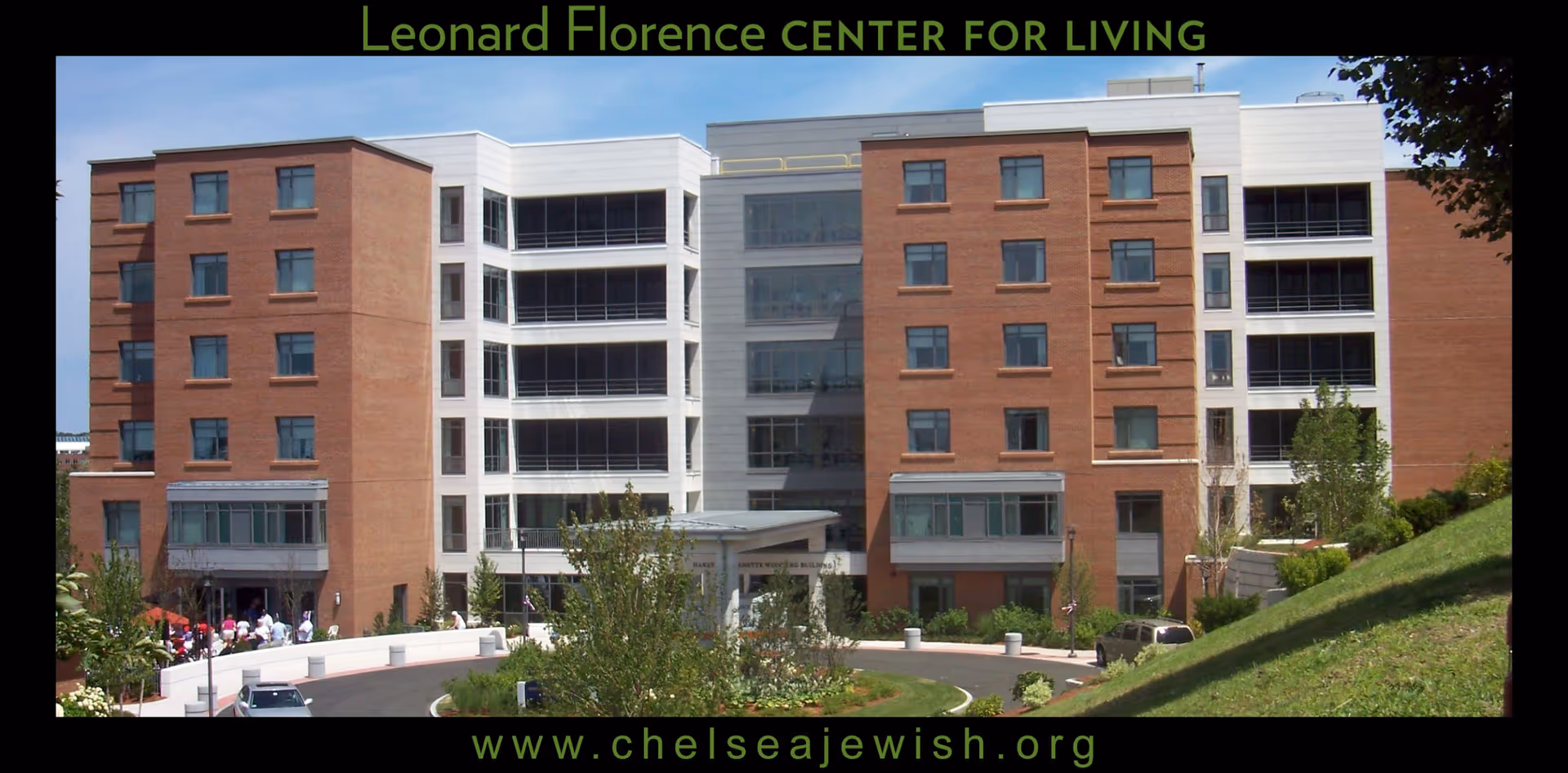 Exterior view of the Leonard Florence Center for Living, a multi-story building with a combination of brick and white paneling. The building has many windows and a driveway with landscaped greenery in front.