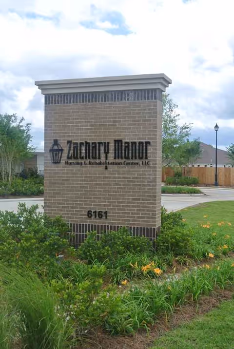 Exterior brick sign for Zachary Manor Nursing and Rehabilitation Center with landscaping