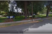 Exterior view of a nursing center with trees, a street, and a sign.