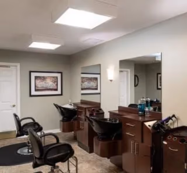 Small salon interior with styling chairs, wash sinks, mirrors, and wooden stations under recessed lighting.