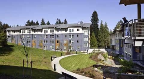 Exterior view of Creekside Woods senior living campus with curved path and balconies.