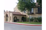 Exterior view of Spanish Meadows of Brownsville with arched entrance and landscaping.