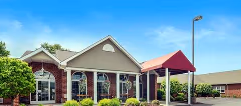 Exterior view of a brick senior living facility with arched windows and a covered entrance.