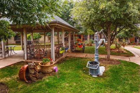 Outdoor courtyard with gazebo, seating, planters, and garden sculptures.