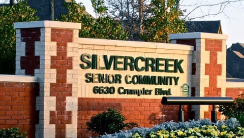 Stone entrance sign reading 'SILVERCREEK SENIOR COMMUNITY 6630 Crumpler Blvd' with landscaping in front.