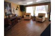 Small sitting area with two armchairs and a side table by a large window, a wooden console with decor and wall art on the left.