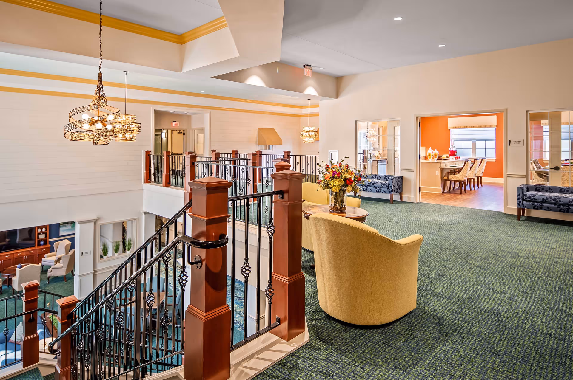 Bright second-floor common area with seating, a decorative staircase and a view into a dining room.