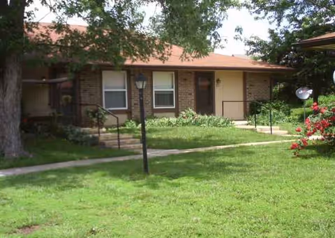 Brick one-story senior apartment building with a lawn and walkway in front.