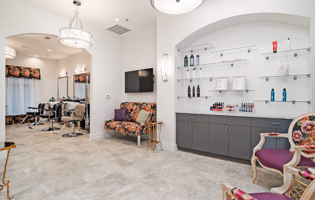 Salon-style interior with styling chairs and mirrors, product shelves, and floral-pattern seating.