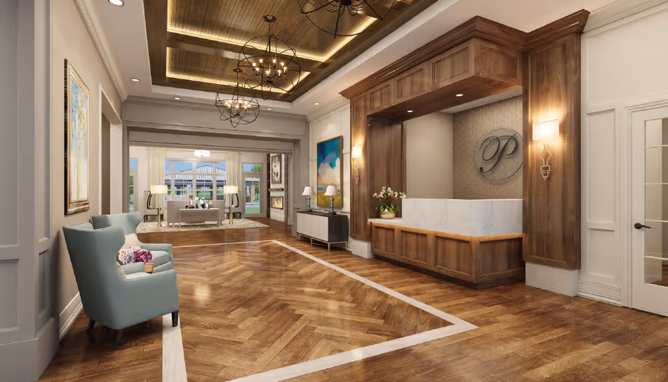 A spacious and elegant interior lobby area with polished wooden herringbone flooring and a wooden reception desk with a marble front. The ceiling features wooden beams with recessed lighting and two modern spherical chandeliers. There is a light blue armchair with a small table holding flowers on the left side, and a seating area with sofas and lamps near large windows in the background. The walls are decorated with framed artwork and sconces.