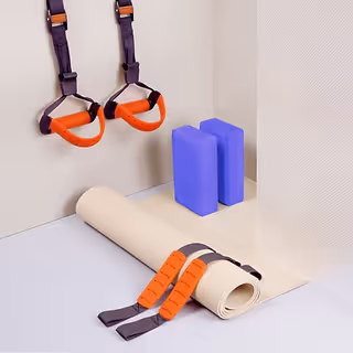 Interior exercise corner with wall-mounted straps, a rolled mat, and blue foam blocks.