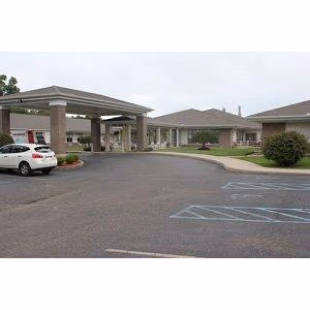 Entrance and porte-cochere of a single-story senior care building with adjacent parking lot and marked accessible spaces.