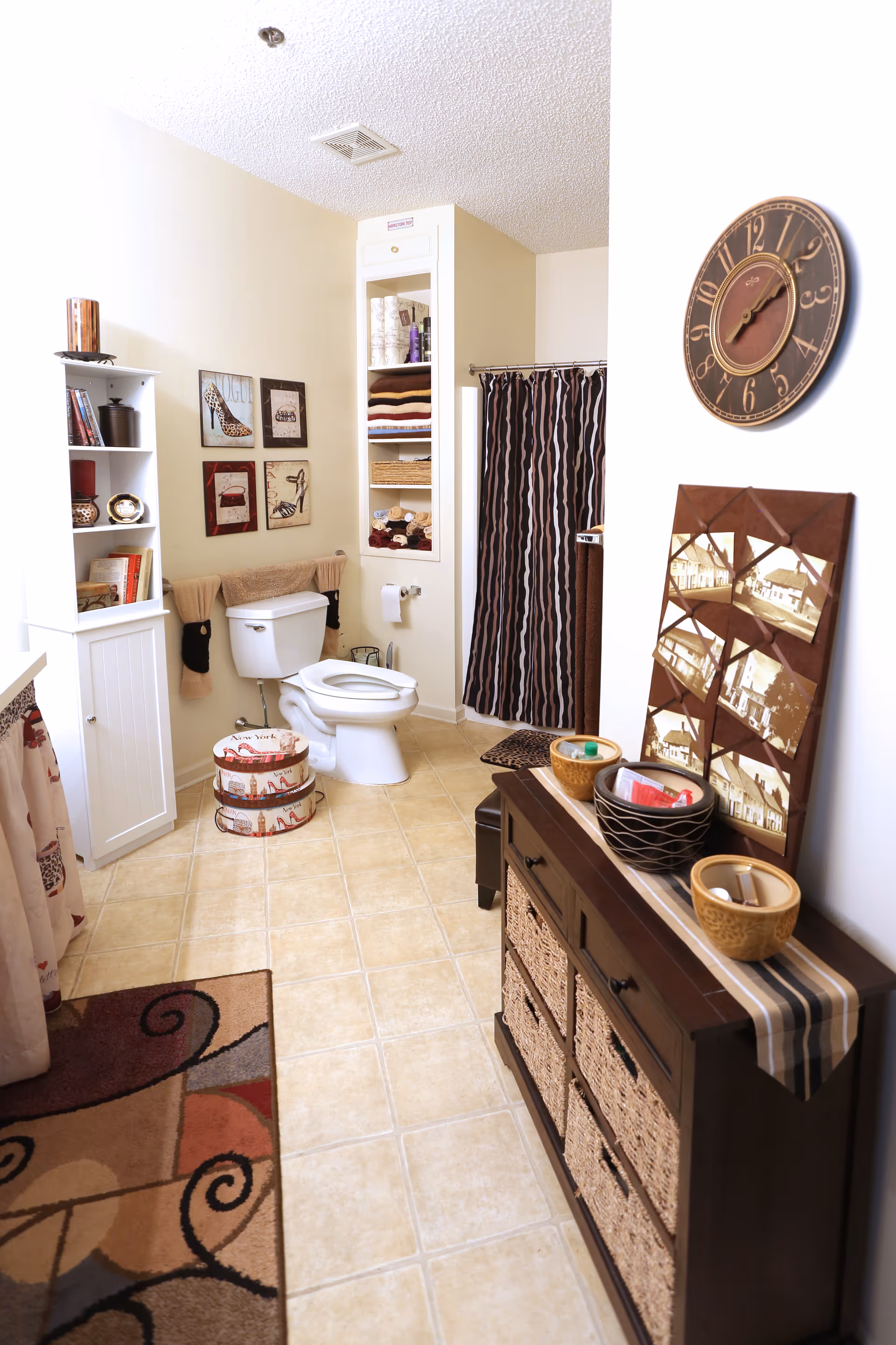Bright, well-decorated bathroom with a toilet, shower curtain, shelving, and a wicker-front cabinet.
