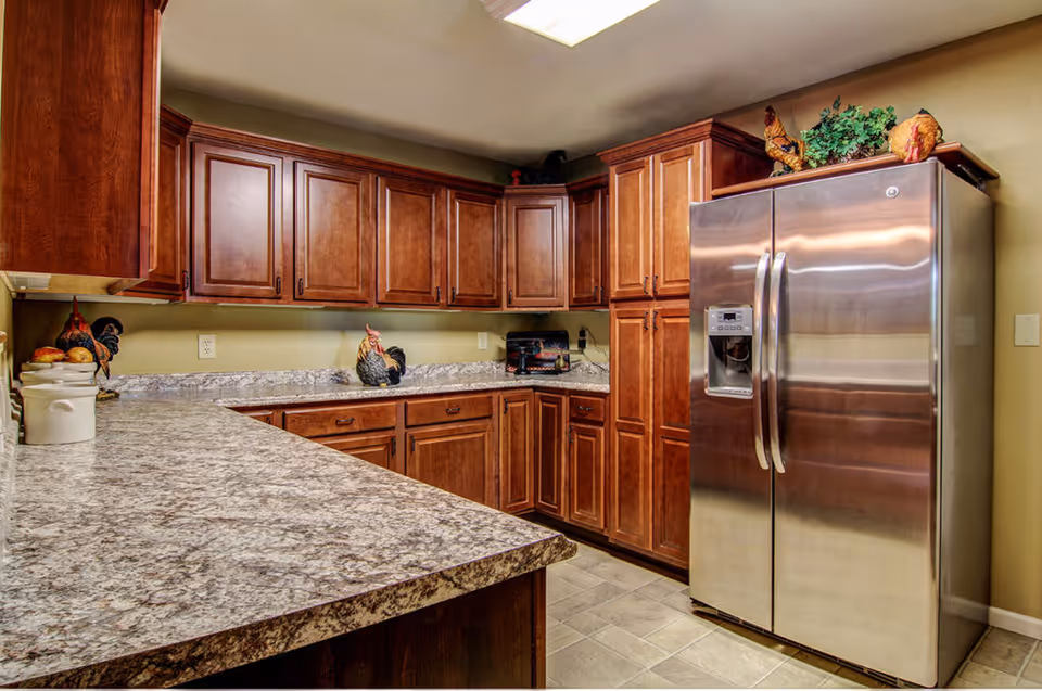 Kitchen with granite-look countertops, wooden cabinets and a stainless steel side-by-side refrigerator.