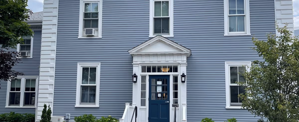 Blue two-story building exterior with a white-framed entrance and dark blue door.